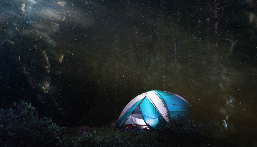 Fotografi på tält i mörk skog